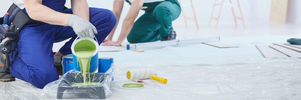 Professional interior painters pouring paint into roller tray.