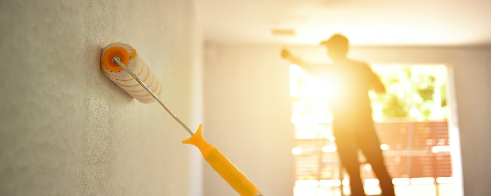 Professional painting company rolling paint on home interior walls.