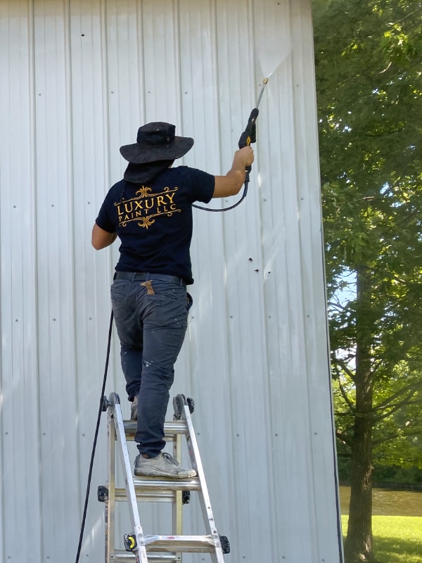 Luxury Paint painter spray painting metal siding on building