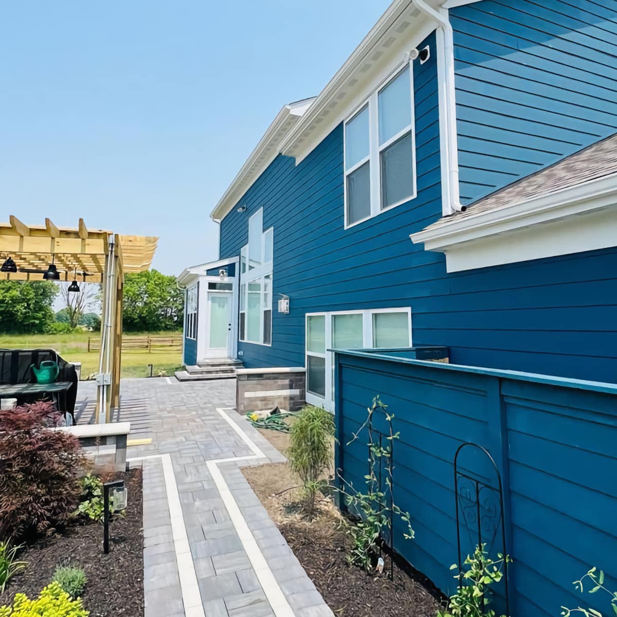 exterior house siding painted a beautiful blue showing backyard with walkway and pergola