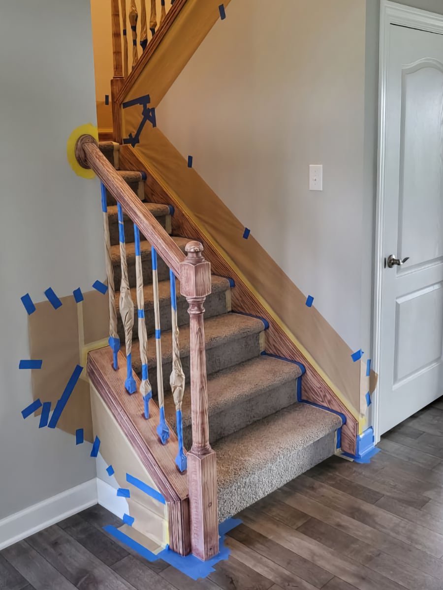 wooden staircase prepped with painters tape and cardboard ready for stain